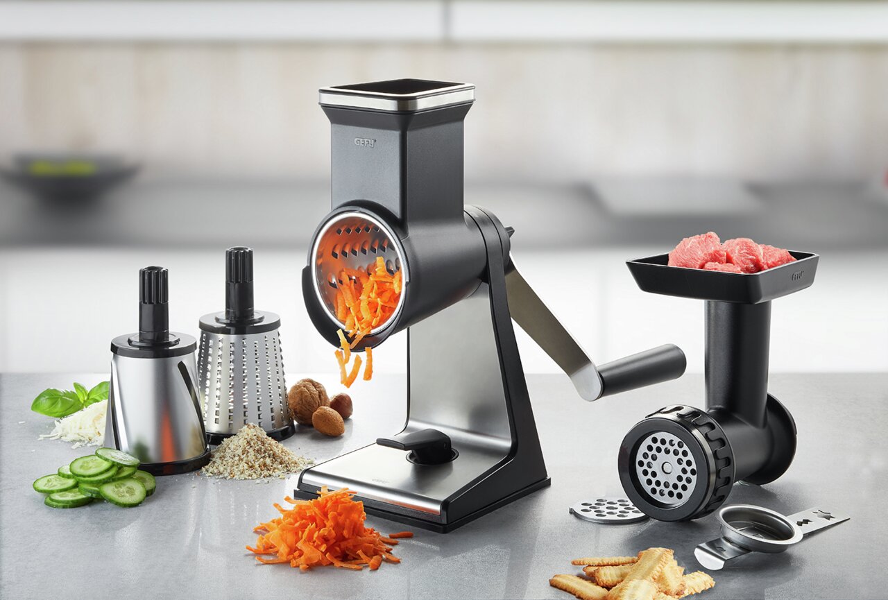 Set bestehend aus Trommelreibe und Fleischwolf, seitliche Perspektive, mit geriebenen Karotten und Fleischstücken.