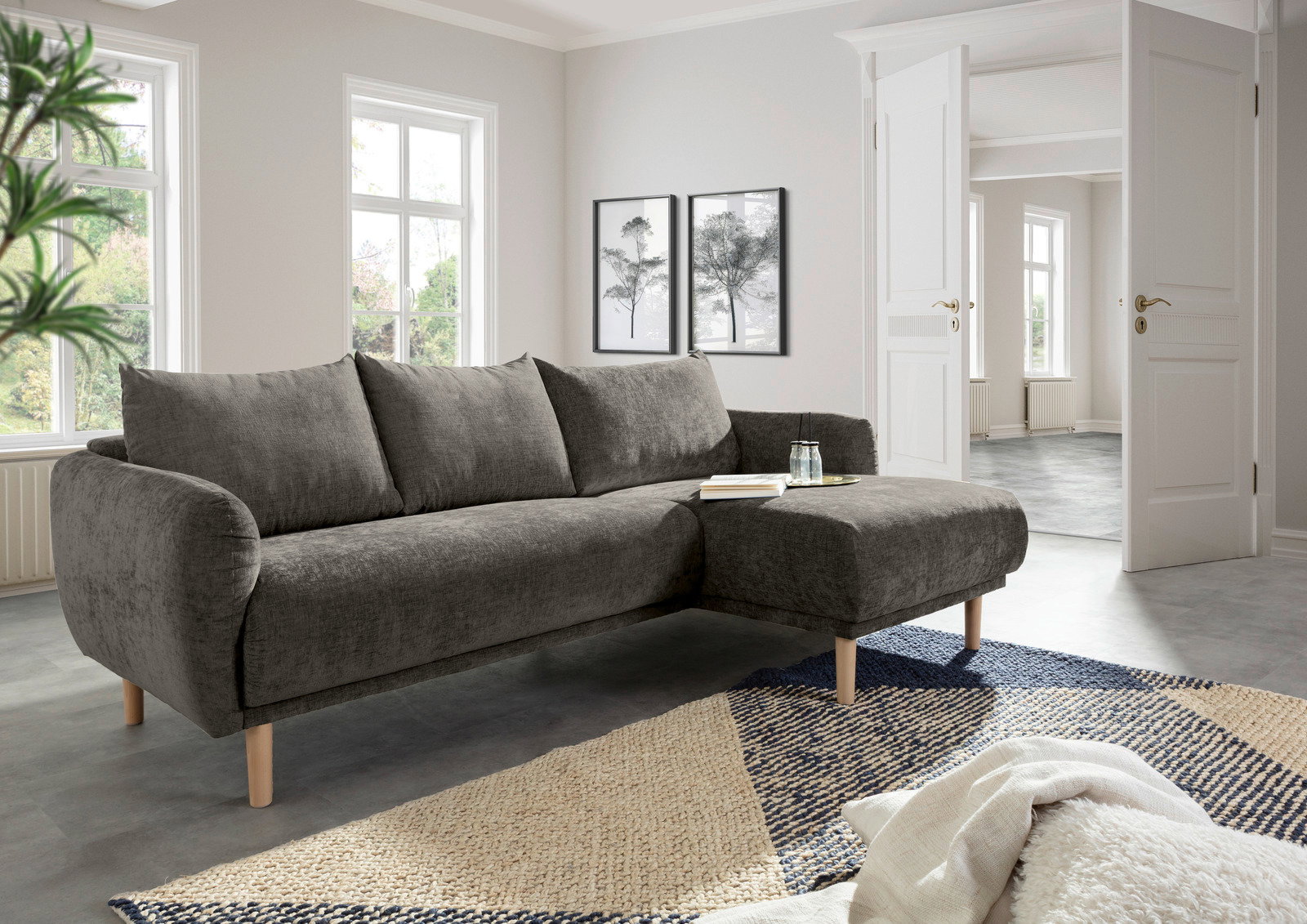 Graues Ecksofa mit Holzfüßen in einem modernen Wohnzimmer, seitliche Perspektive.