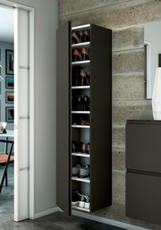 Moderner Hänge-Garderobenschrank in dunklem Design, gefüllt mit Schuhen, an einer Betonwand montiert. Perspektive von vorne links.
