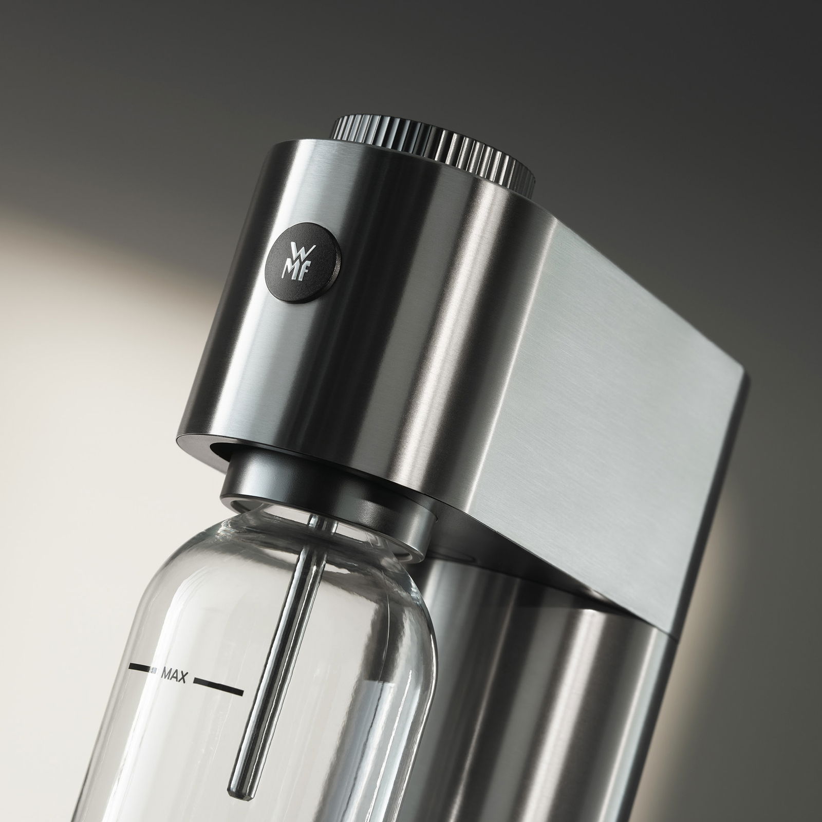 WMF Wassersprudler STEEL ELEMENT ONE Nahaufnahme eines eleganten Wassersprudlers aus Edelstahl mit einer Glasflasche, seitliche Perspektive.