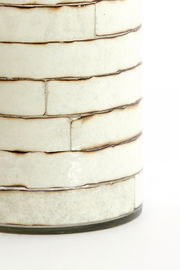 Nahaufnahme eines Teelichthalters mit cremefarbenen, rechteckigen Keramikfliesen und dunklen Fugen, seitliche Perspektive.