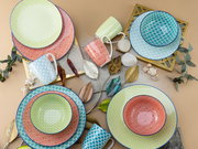 Bunte Geschirrkollektion aus Tellern, Schalen und Tassen mit verschiedenen Mustern in einer stilvollen Anordnung von oben betrachtet.