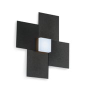 Moderne geometrische Wandleuchte mit vier überkreuz angeordneten schwarzen Paneelen in Holzoptik und zentralem weißem, würfelförmigem Leuchtkörper, aus schräger Vorderansicht gezeigt