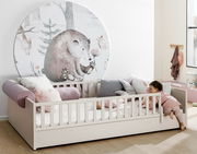 Kinderbett mit Rausfallschutz und Bettkasten, dekoriert mit Kissen und einem Wandbild eines Bären, seitliche Perspektive