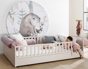 Kinderbett mit Rausfallschutz und Bettkasten, dekoriert mit Kissen und einem Wandbild eines Bären, seitliche Perspektive