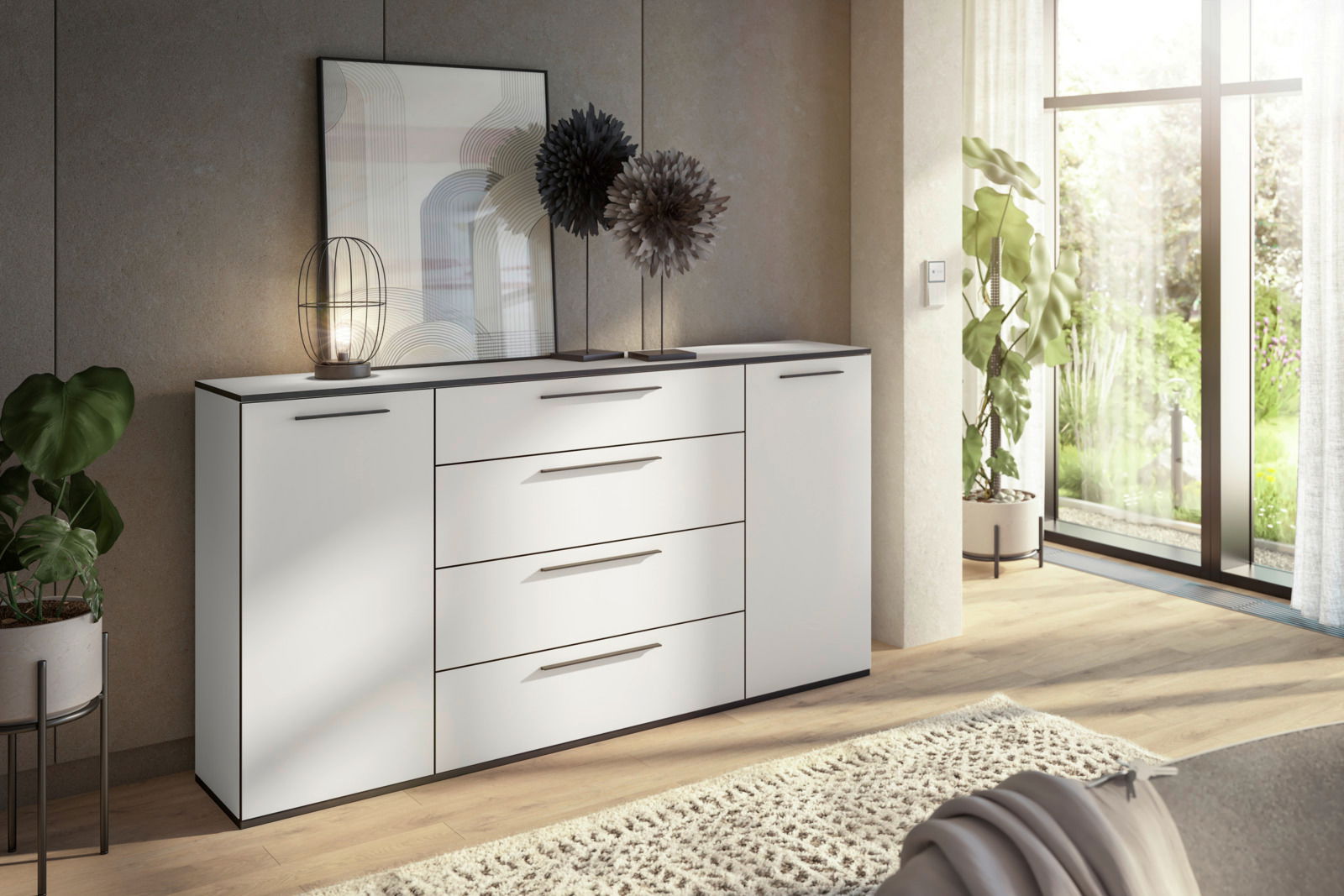 Novel XL-dressoir SOUL Modernes weißes Sideboard mit Schubladen und Türen, dekoriert mit einer Lampe und Kunstobjekten, in einem hellen Raum mit Blick auf den Garten. Perspektive von schräg vorne.
