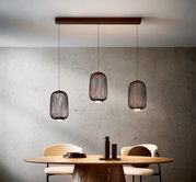 Moderne LED-Hängeleuchte mit drei zylinderförmigen Lampenschirmen aus Metall, hängend über einem Esstisch, seitliche Perspektive.