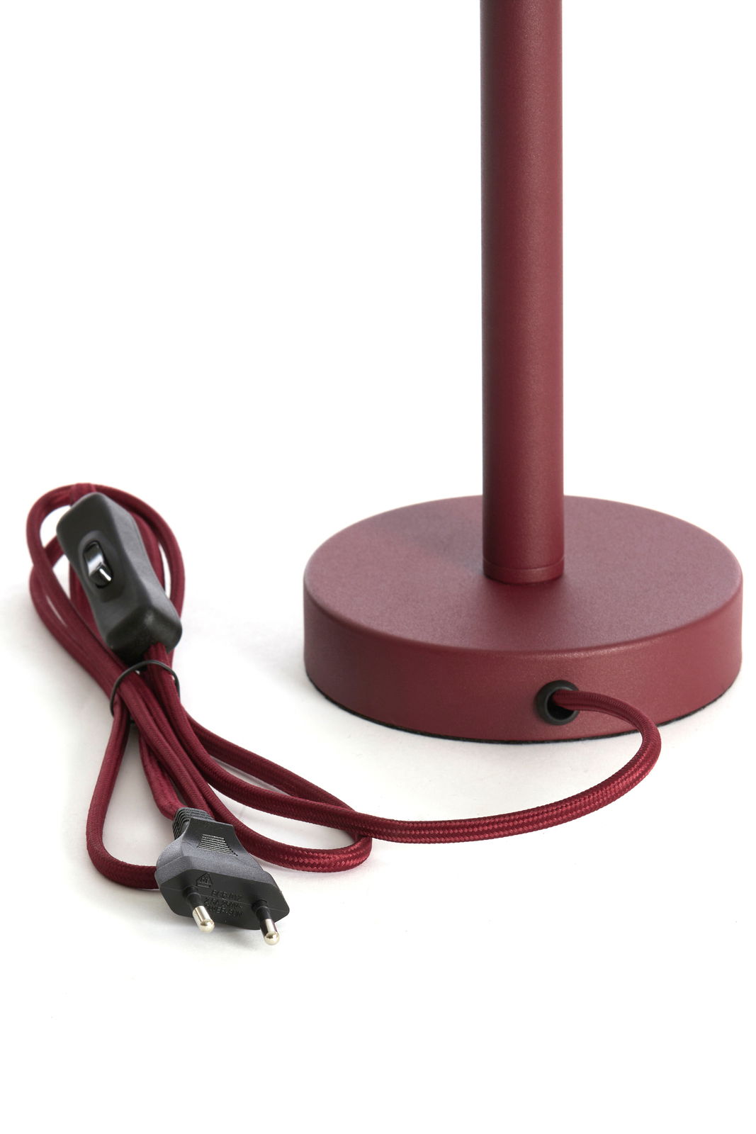Nahaufnahme eines bordeauxroten Lampenfußes mit rundem Sockel und passendem Kabel mit Schalter und Stecker, seitliche Perspektive.