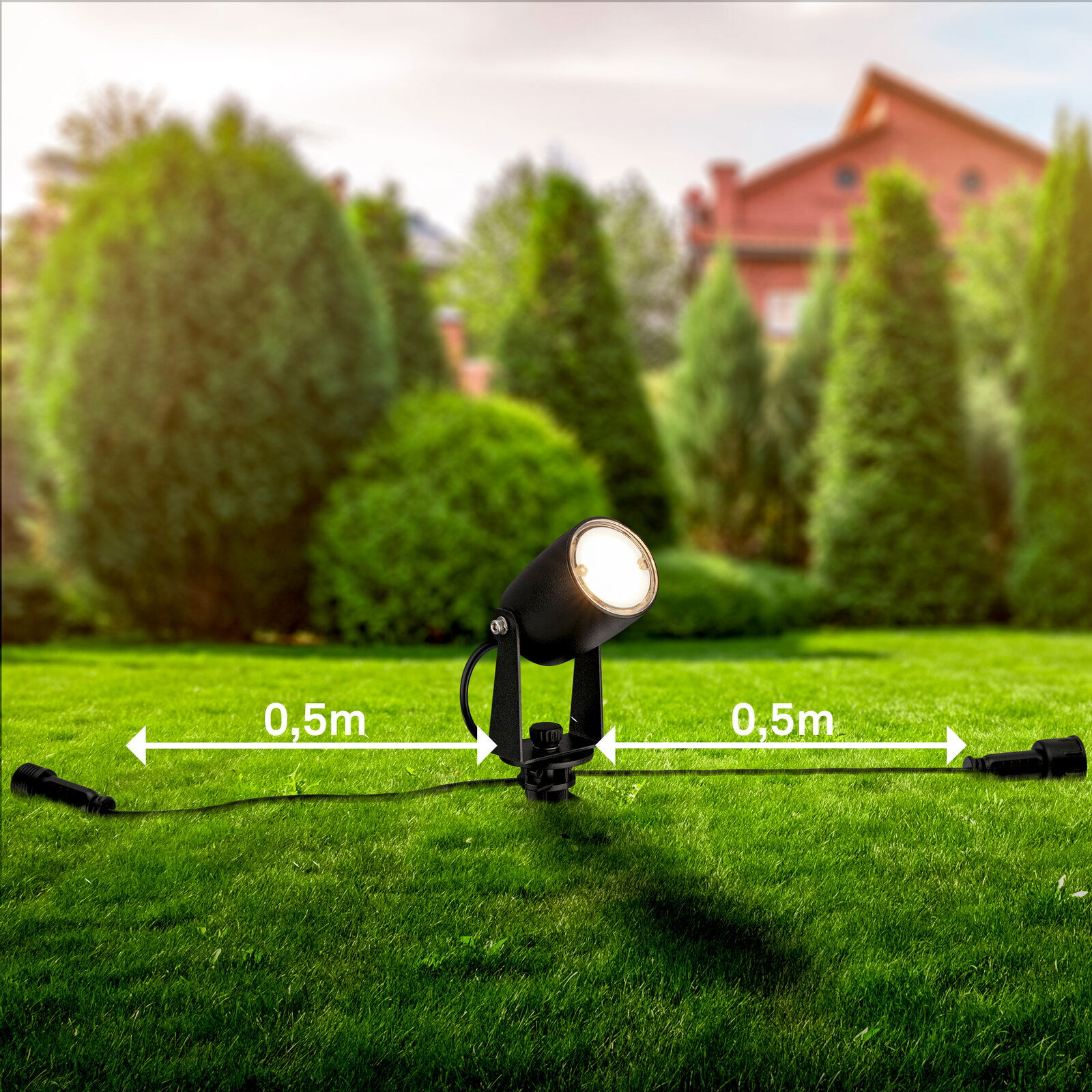 Bodenspot auf einer grünen Rasenfläche mit einem Abstand von 0,5 m zu beiden Seiten, im Hintergrund sind Bäume und ein Haus zu sehen, seitliche Perspektive.