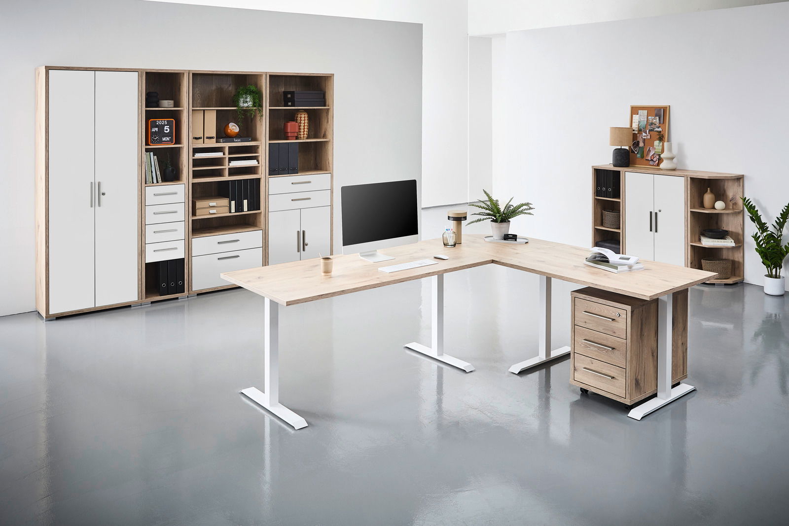 Voleo Schreibtisch CONNECT Moderne Büromöbel in einem hellen Raum, bestehend aus einem L-förmigen Schreibtisch mit Holzoberfläche und weißen Beinen, einem Rollcontainer und mehreren Regalen mit Schubladen und Türen. Perspektive von vorne.