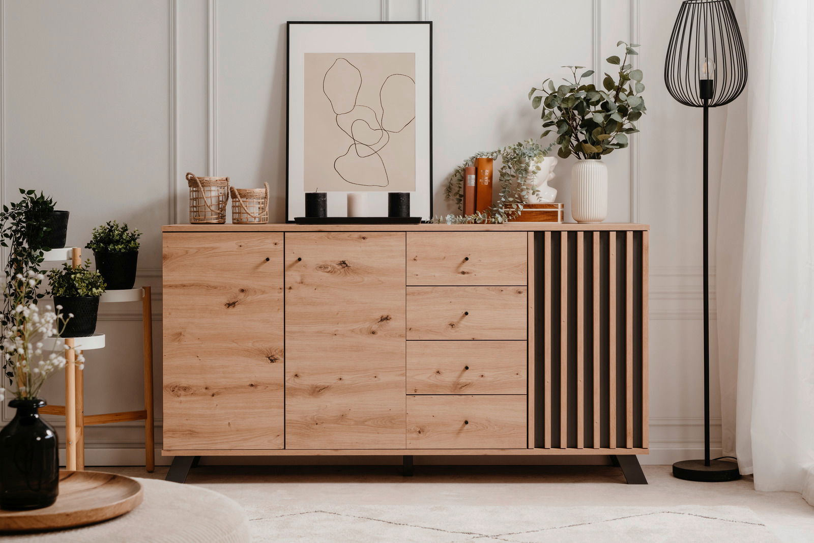 Modernes Sideboard aus Holz mit Schubladen und Türen, dekoriert mit Pflanzen und Kunstobjekten, frontal fotografiert.