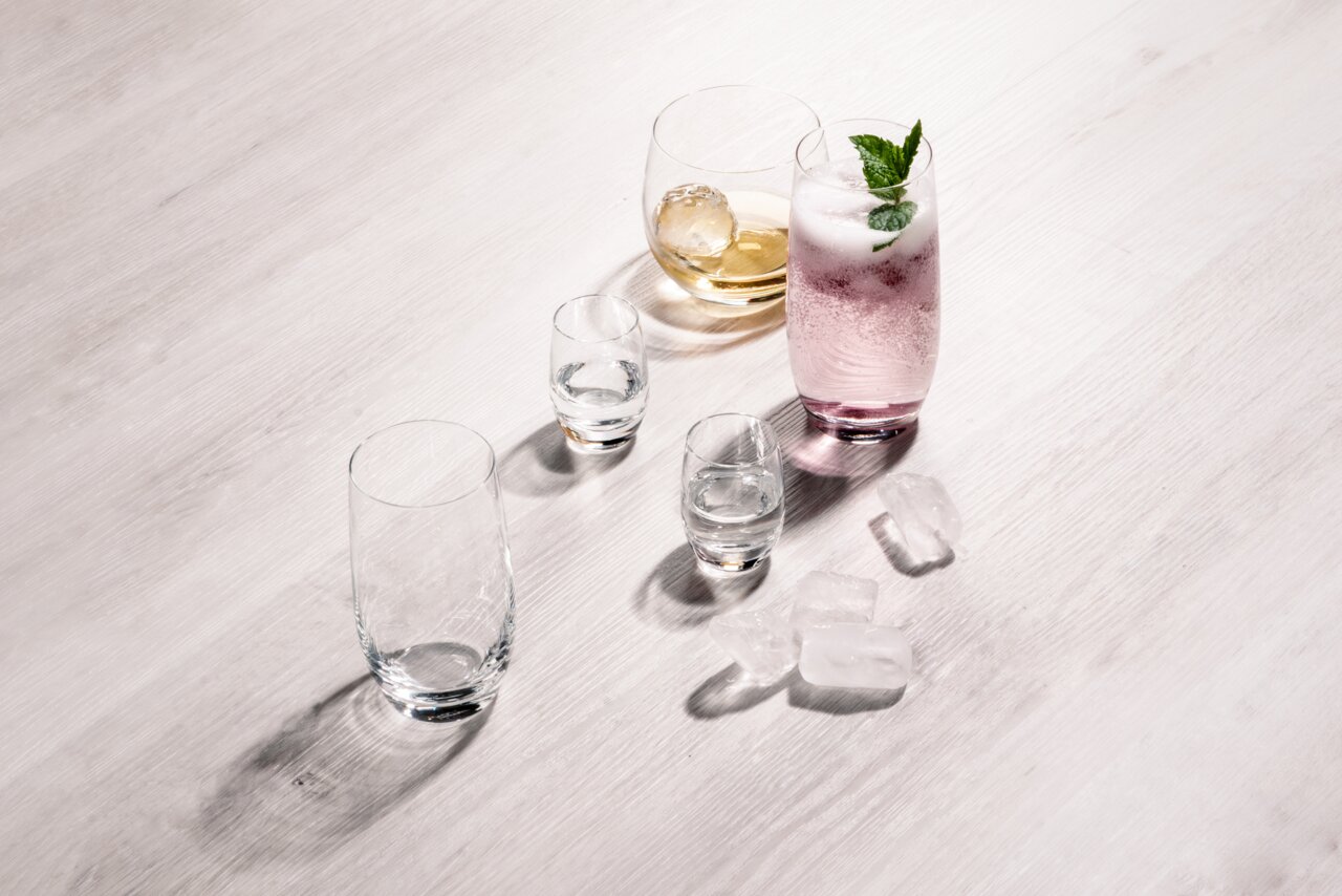 Verschiedene Gläser auf einem Tisch, darunter ein Bierbecher-Set aus vier Gläsern, aus der Vogelperspektive fotografiert.
