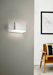 Moderne Wand- und Deckenleuchte SANIA 4 in rechteckiger Form, seitliche Perspektive, montiert an einer grauen Wand neben einem stilvollen Sessel und einem gerahmten Bild.