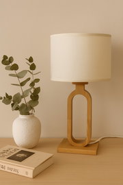 Moderne Tischleuchte mit ovalem Holzfuß und cremefarbenem Lampenschirm, seitliche Perspektive