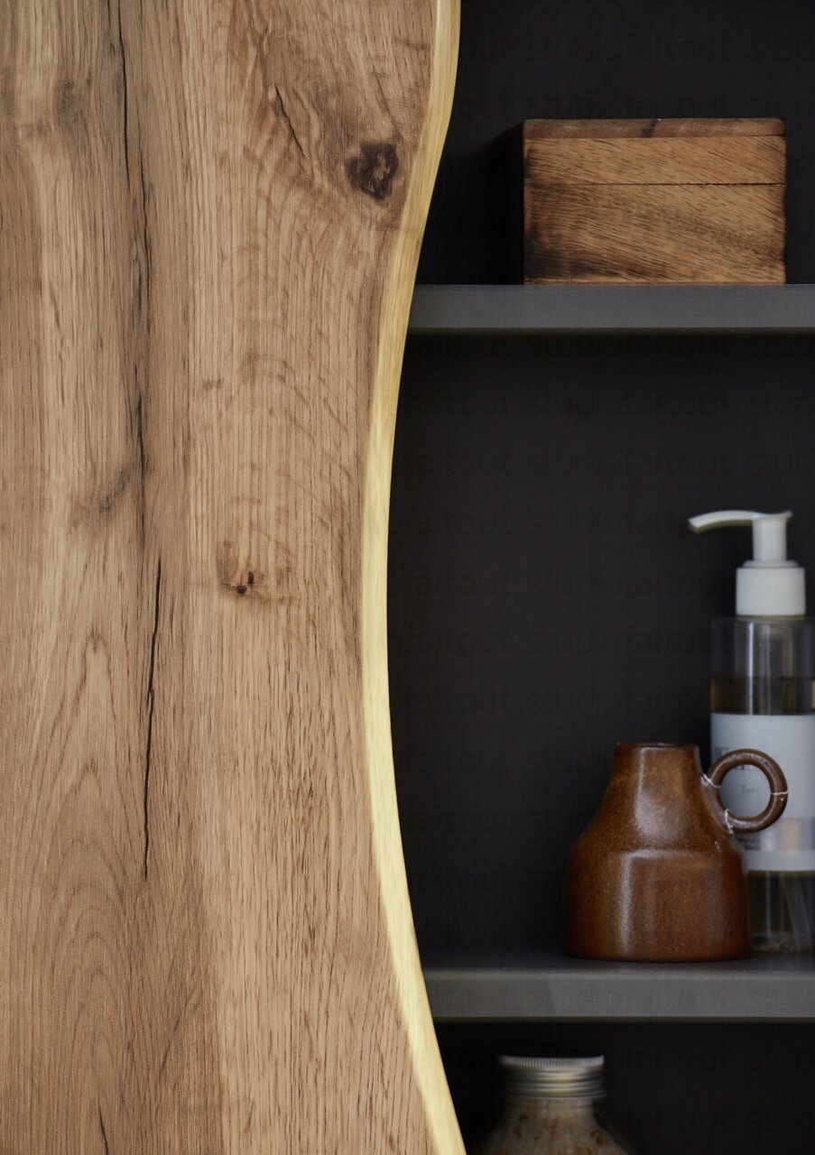 Close-up van een onderkast met natuurlijke houtnerf en planken met accessoires, zijaanzicht