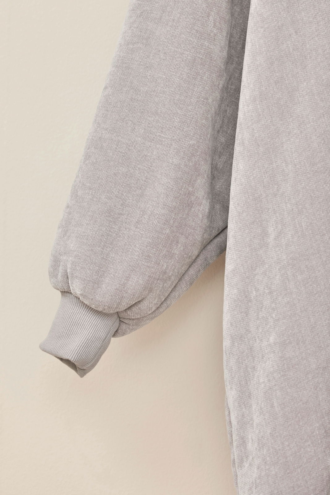 Nahaufnahme eines grauen Lounge Hoodies mit weichem Stoff und geripptem Bündchen, seitliche Perspektive