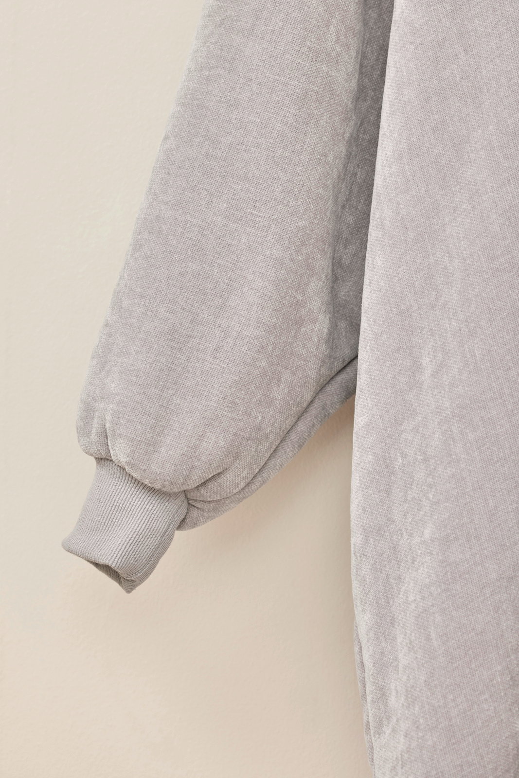 Nahaufnahme eines grauen Lounge Hoodies mit weichem Stoff und geripptem Bündchen, seitliche Perspektive
