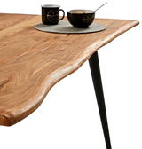 Nahaufnahme eines Esstisches mit natürlicher Holzmaserung und schwarzem Metallbein, von der Seite betrachtet.