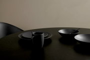 Schwarzes Kombiservice Bella Vista 24-teilig auf einem Tisch, bestehend aus Tellern, Schalen und einer Tasse, aus seitlicher Perspektive fotografiert.