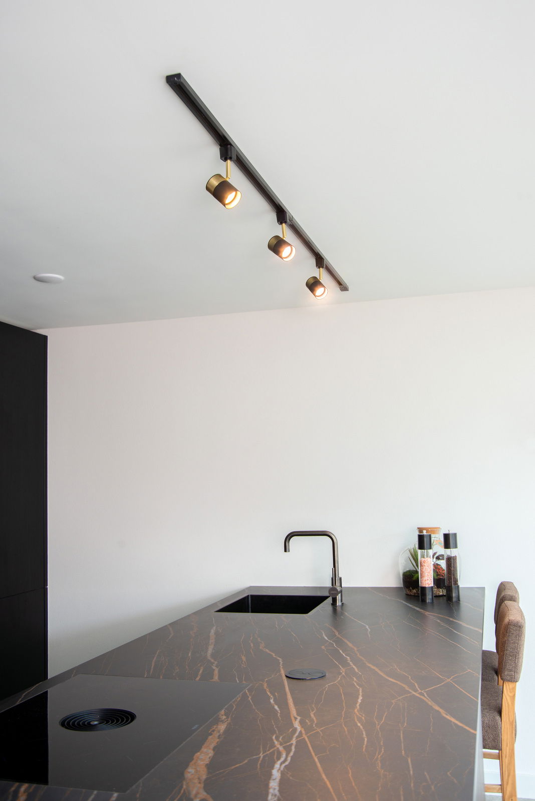 Deckenstrahler FLORIS in Schwarz mit drei verstellbaren Leuchten, montiert über einer modernen Kücheninsel. Perspektive von unten nach oben.