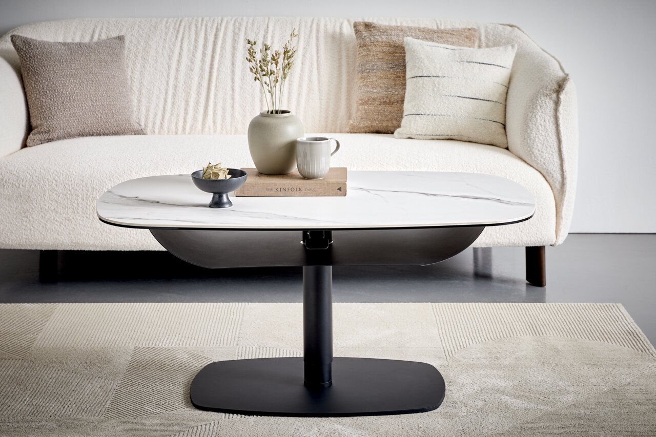 Dieter Knoll Salontafel BRESCIA Moderne salontafel met een wit marmeren blad en een zwart metalen onderstel, die voor een crèmekleurige bank staat.