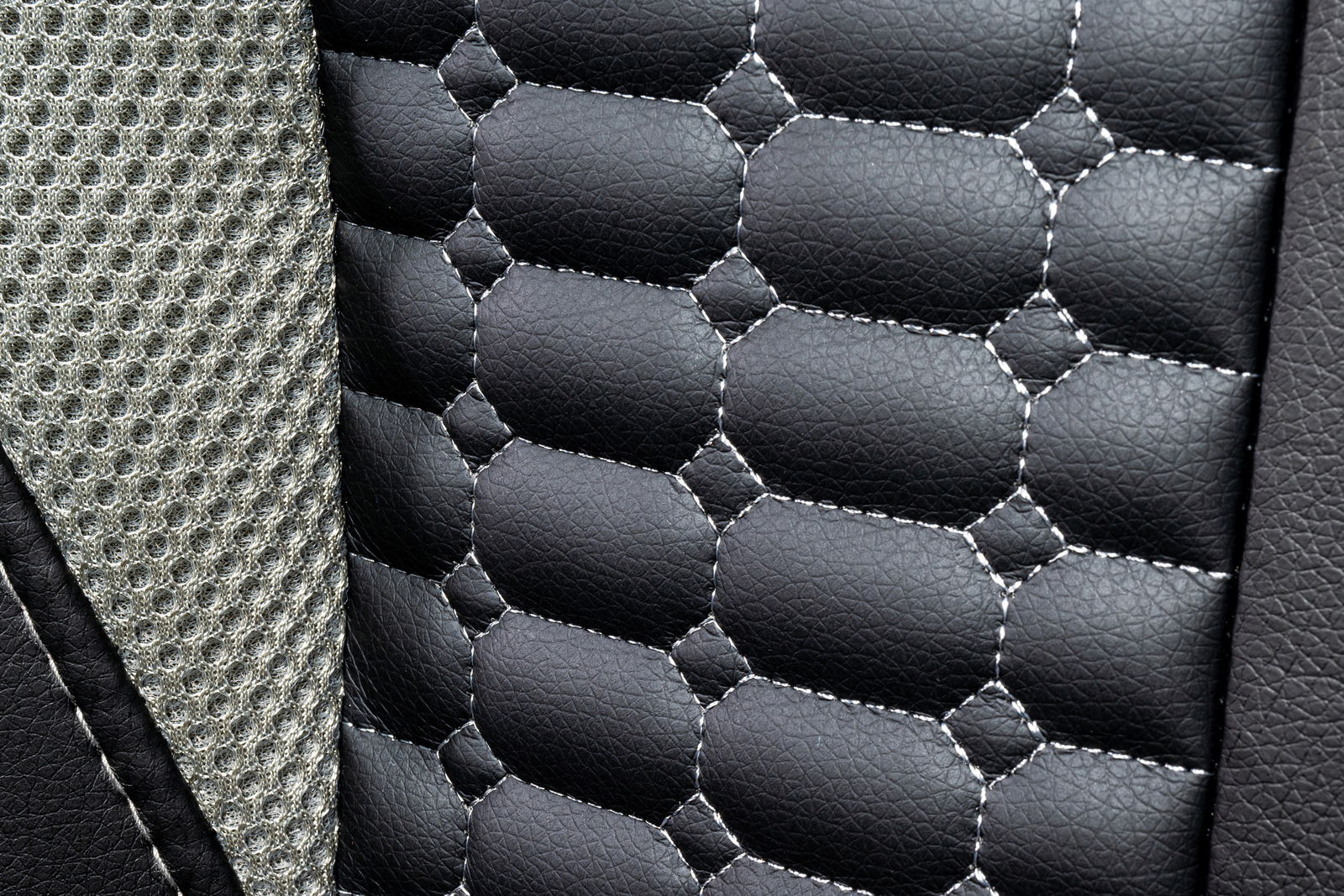 Nahaufnahme der Polsterung eines Gaming-Stuhls mit schwarzem Kunstleder und grauem Netzstoff.