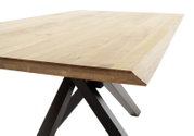 Nahaufnahme eines Esstisches aus Holz mit abgeschrägten Kanten und schwarzen Metallbeinen, seitliche Perspektive.