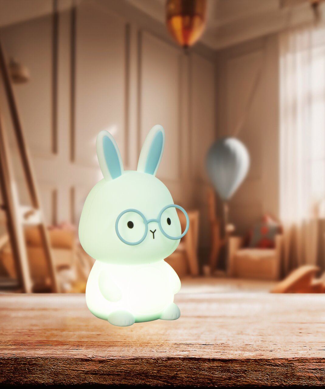 Niedliches Akku-Nachtlicht in Form eines Hasen mit Brille, frontal auf einem Tisch in einem gemütlichen Raum platziert.