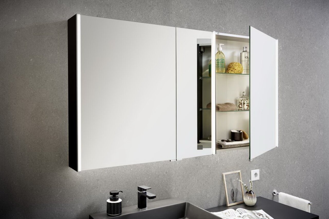 Spiegelschrank im Badezimmer mit geöffneter Tür, zeigt Regale mit Pflegeprodukten, seitliche Perspektive
