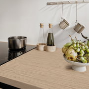 Moderne Küchenarbeitsplatte mit Induktionskochfeld, Topf, Öl- und Essigflaschen sowie einer Schale mit frischem Obst, aus der Perspektive von oben betrachtet.