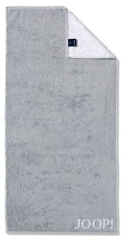 Graues Handtuch mit eingewebtem 'JOOP!' Logo, von oben fotografiert, mit umgeschlagener Ecke, die die weiße Rückseite zeigt.