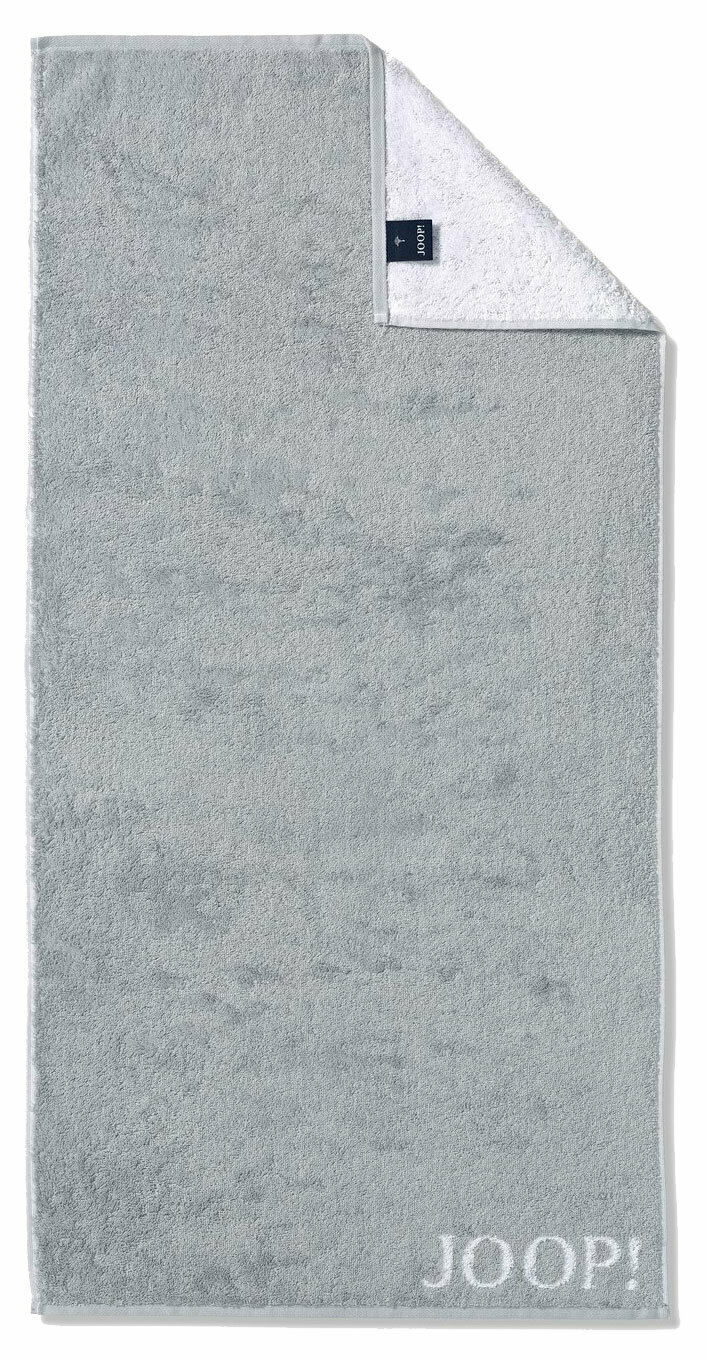 Graues Handtuch mit eingewebtem 'JOOP!' Logo, von oben fotografiert, mit umgeschlagener Ecke, die die weiße Rückseite zeigt.