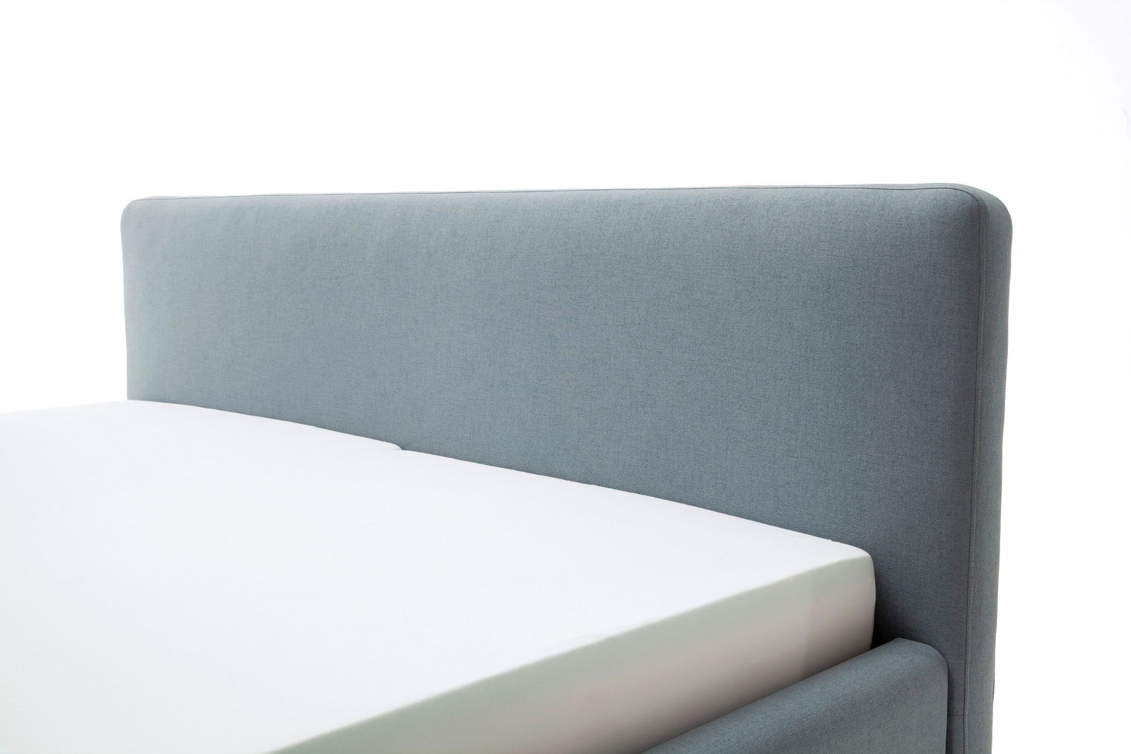 Nahaufnahme eines grauen Polsterbetts mit Kopfteil, seitliche Perspektive