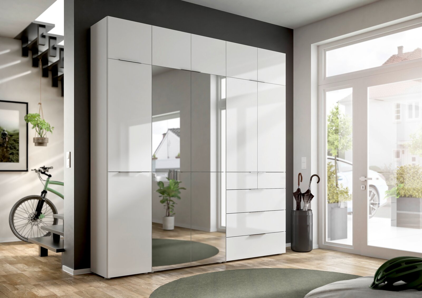Moderner weißer Kleiderschrank mit Spiegeltüren und Schubladen, perspektivisch von vorne rechts fotografiert, in einem hellen Raum mit großen Fenstern.