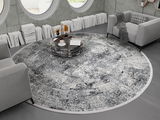 Runder Designer Teppich in einem modernen Wohnzimmer mit grauen Sofas und einem runden Couchtisch, von oben betrachtet.