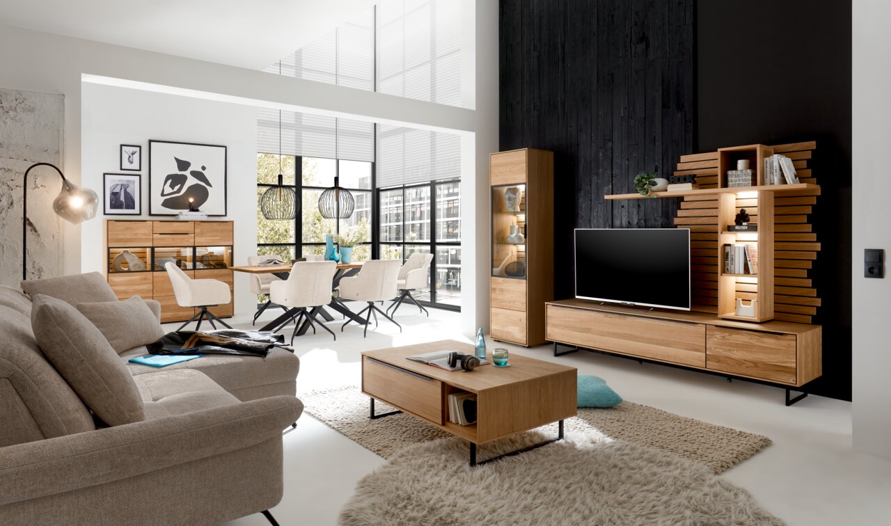 Moderner Wohnraum mit einem Couchtisch aus Holz in der Mitte, umgeben von einem Sofa und einem TV-Lowboard. Perspektive: Frontalansicht auf den Couchtisch.