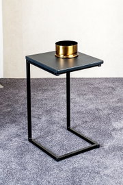 Schwarzer, minimalistischer Beistelltisch aus Metall mit U-förmigem Gestell auf grauem Teppich, darauf eine goldene Schale; fotografiert aus leicht erhöhter Front-/Schrägansicht.