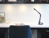 Moderne schwarze Tischleuchte aus Kunststoff auf einem Schreibtisch, seitliche Perspektive