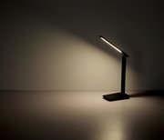 Moderne schwarze Tischleuchte mit schlankem Design, seitliche Perspektive, leuchtet eine Wand an.