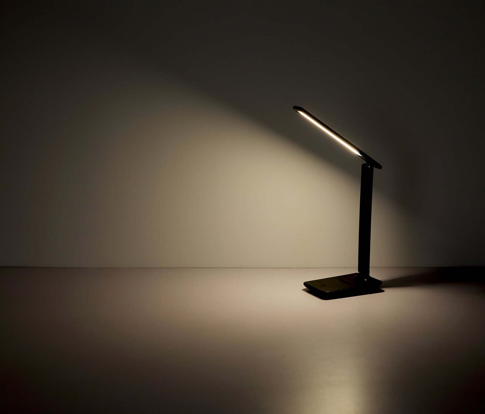 Moderne schwarze Tischleuchte mit schlankem Design, seitliche Perspektive, leuchtet eine Wand an.