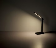 Moderne schwarze Tischleuchte mit schlankem Design, seitliche Perspektive, leuchtet eine Wand an.