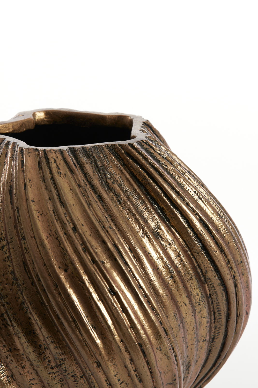 Nahaufnahme einer dekorativen Vase mit geriffelter, antik wirkender Oberfläche in Bronzeoptik, von oben betrachtet.