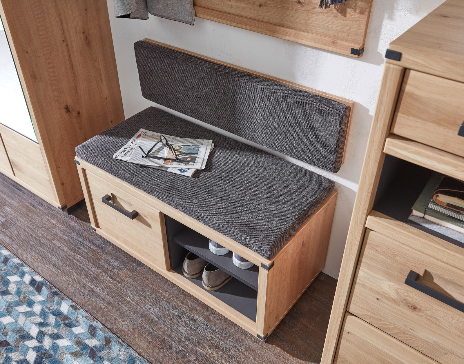 Garderobenbank aus Holz mit grauem Polster, zwei Schubladen und offenen Fächern, seitliche Perspektive