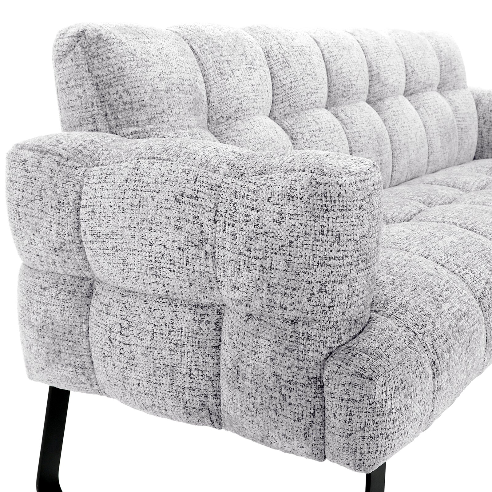 Detailaanzicht vanuit schuin vooraanzicht van een lichtgrijze, gemêleerde fauteuil met zachte blokstiksels, brede armleuning en zwarte metalen poten