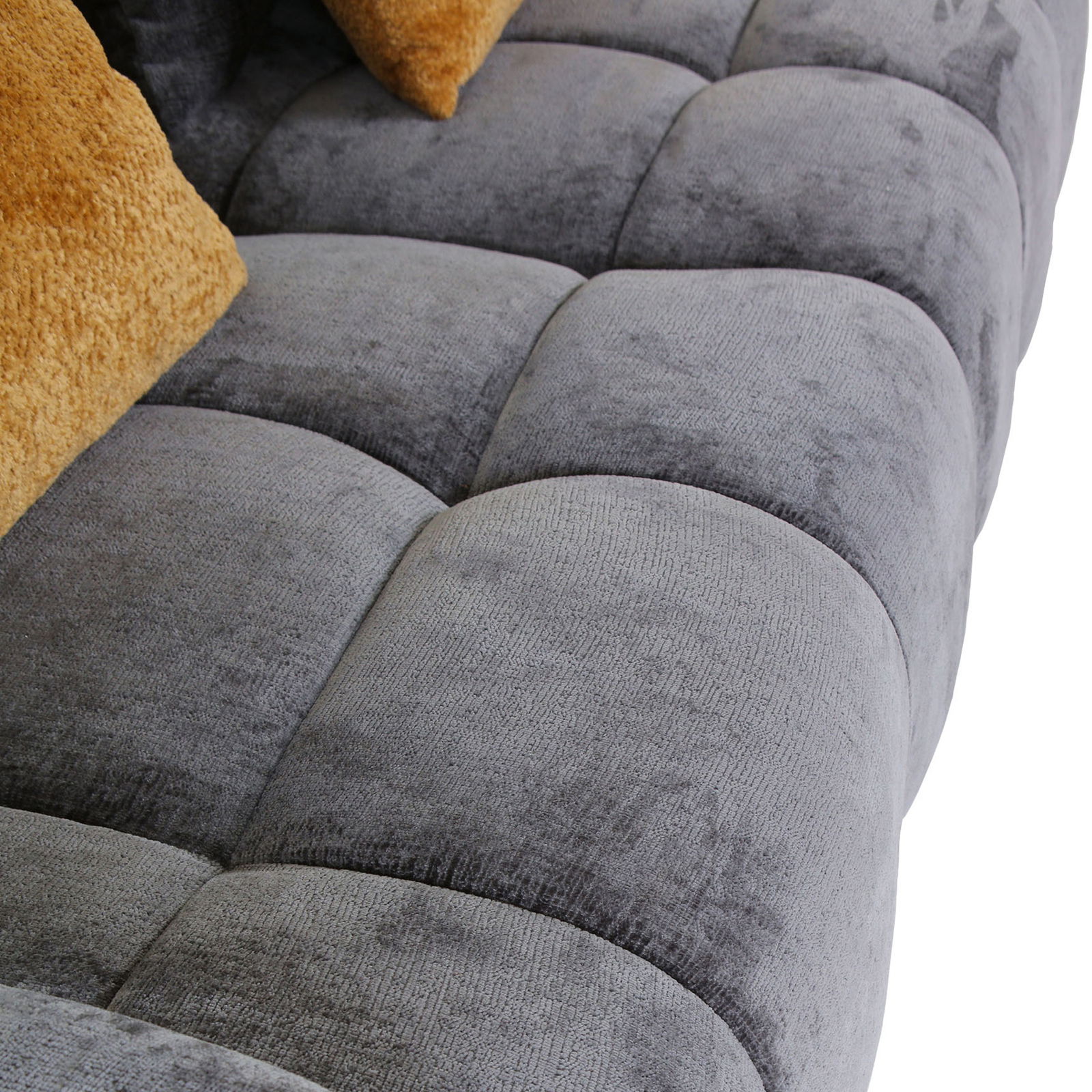 Nahaufnahme eines grauen Megasofas mit weicher, gepolsterter Oberfläche und beigen Kissen, seitliche Perspektive.
