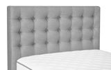 Graues, gestepptes Kopfteil eines Boxspringbetts mit weißer Matratze, seitliche Perspektive