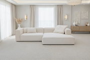 Crèmekleurige L-vormige hoekbank met chaise longue in een lichte, minimalistische woonkamer met grote ramen en beige gordijnen, frontaal perspectief