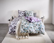 Beddengoedset met geometrisch patroon in grijs, blauw en paars op een bed, gefotografeerd vanuit een vooraanzicht.