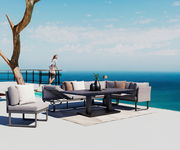 Moderner Gartentisch auf einer Terrasse mit Meerblick, umgeben von stilvollen grauen Sofas und Dekorationen, aus der Perspektive eines seitlichen Blicks.