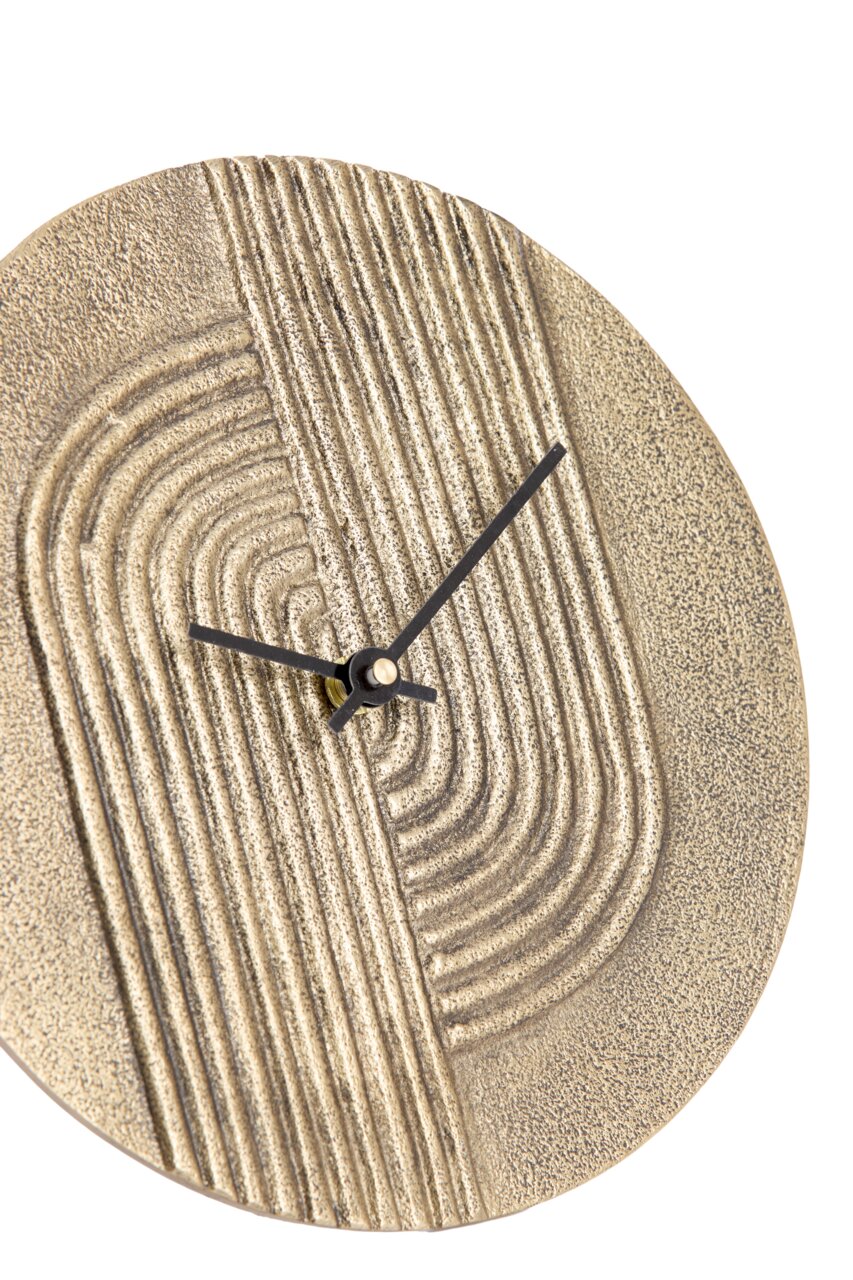 Nahaufnahme einer dekorativen Wanduhr mit strukturiertem, goldfarbenem Zifferblatt und schwarzen Zeigern.